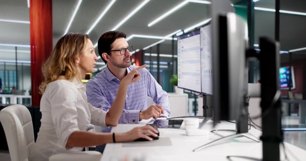 Two human resources employees look at a software dashboard and explore new AI use cases in HR.