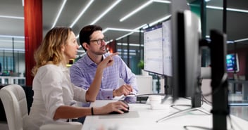 Two human resources employees look at a software dashboard and explore new AI use cases in HR.