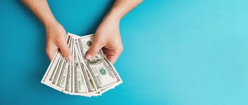 Hand with money fanned out to represent savings