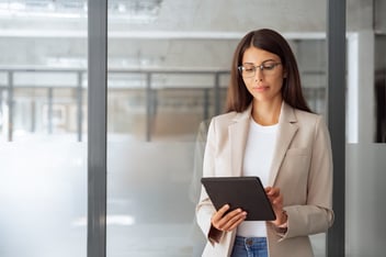 HR tech solutions for brokers: HR manager wearing a pair of eyeglasses, using a tablet