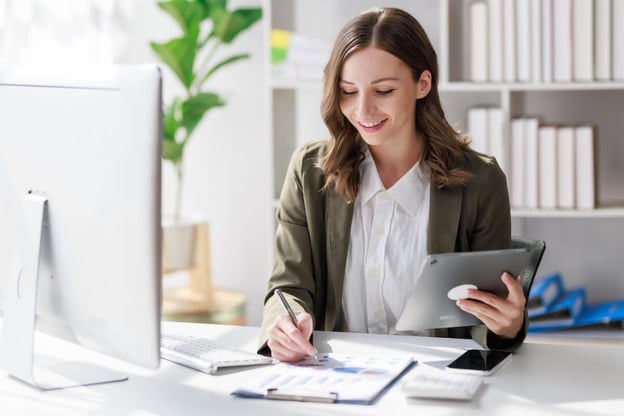 Employee benefits administration: employee holding a tablet while writing on a document