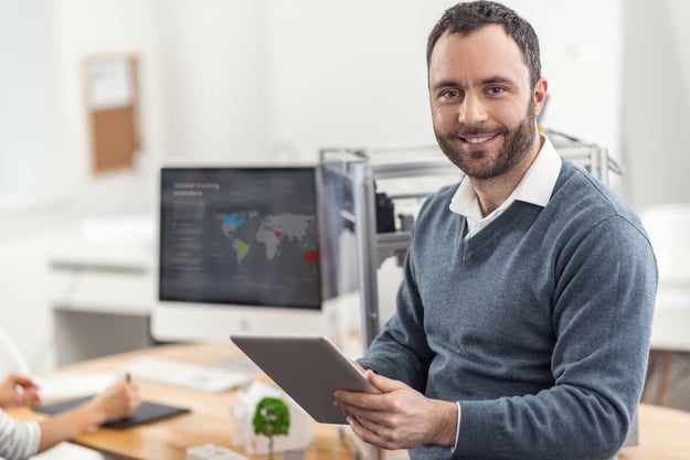 Employee smiling at the camera while holding a tablet