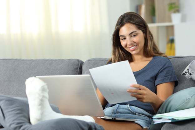 Woman with a leg injury happily working at home