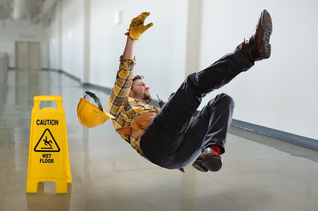 Man slipping beside a wet floor signage
