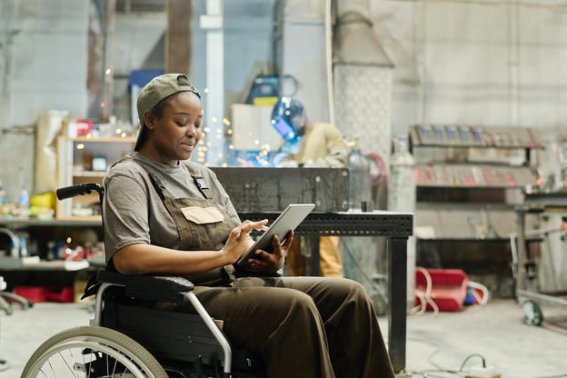Worker sitting in a wheelchair while using a tablet