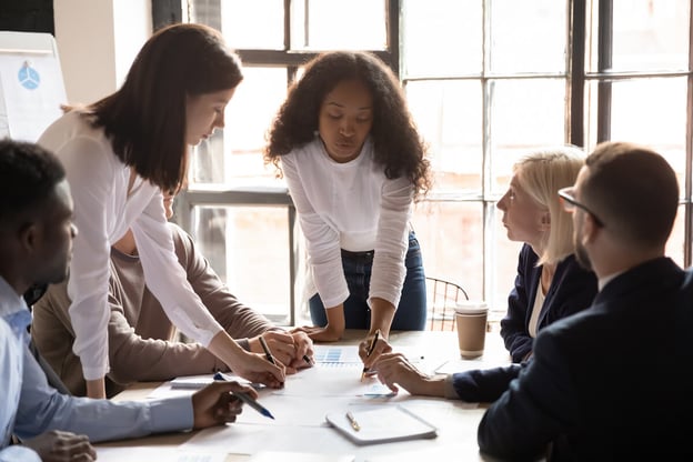 Benefits administration: Boss writes on paper while team looks on