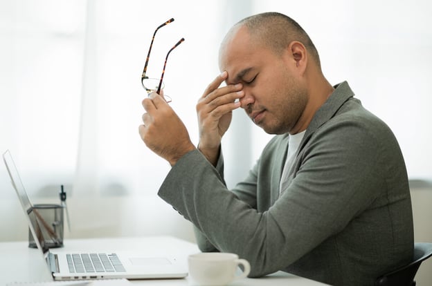 FMLA Washington: stressed man holding his eyeglasses while massaging the bridge of his nose