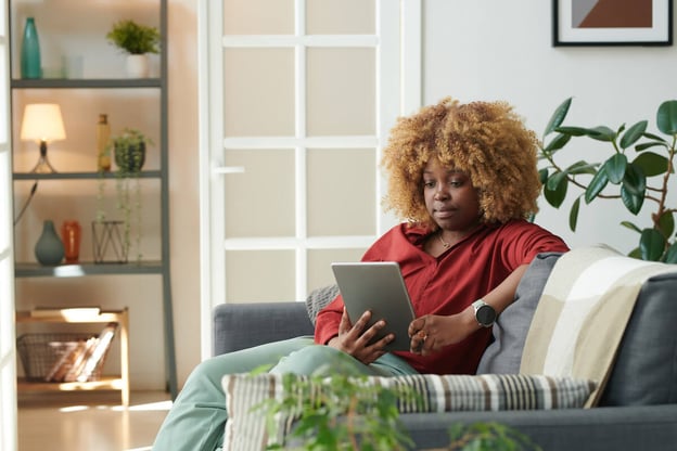 Woman using a tablet while sitting on a couch