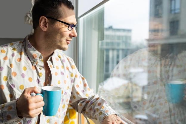 FMLA intermittent leave: man looking out the window while holding a mug