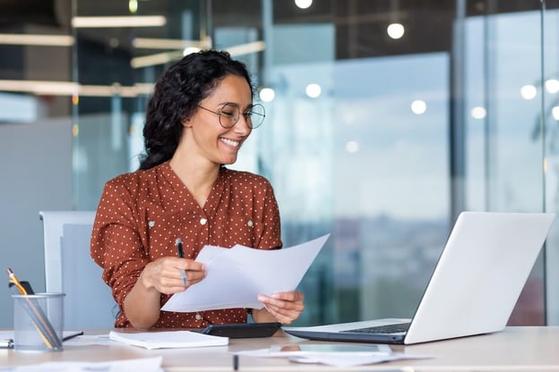 Streamline workflow: entrepreneur holding some documents while looking at a laptop