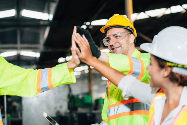 Accident investigation: workers wearing hard hats high-fiving each other