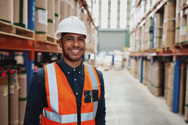Happy engineer in a warehouse wearing a hard hat