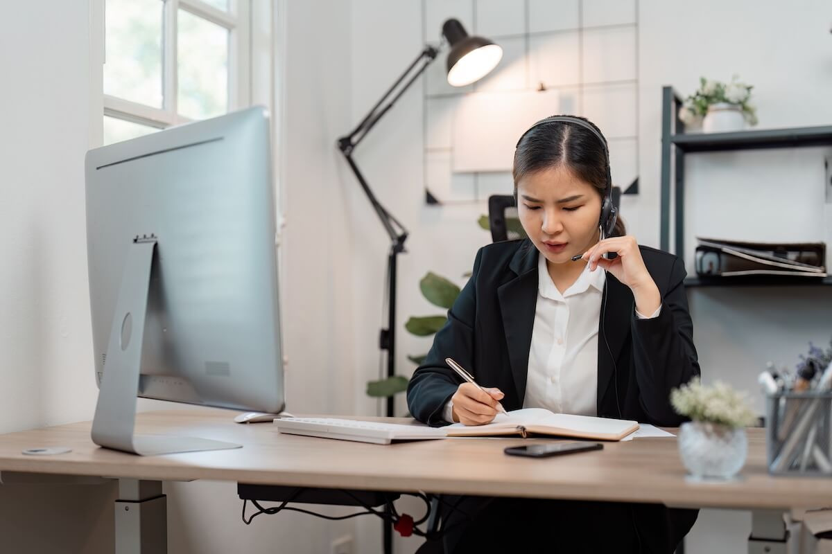 Performance improvement process: call center agent writing in a notebook while on a call