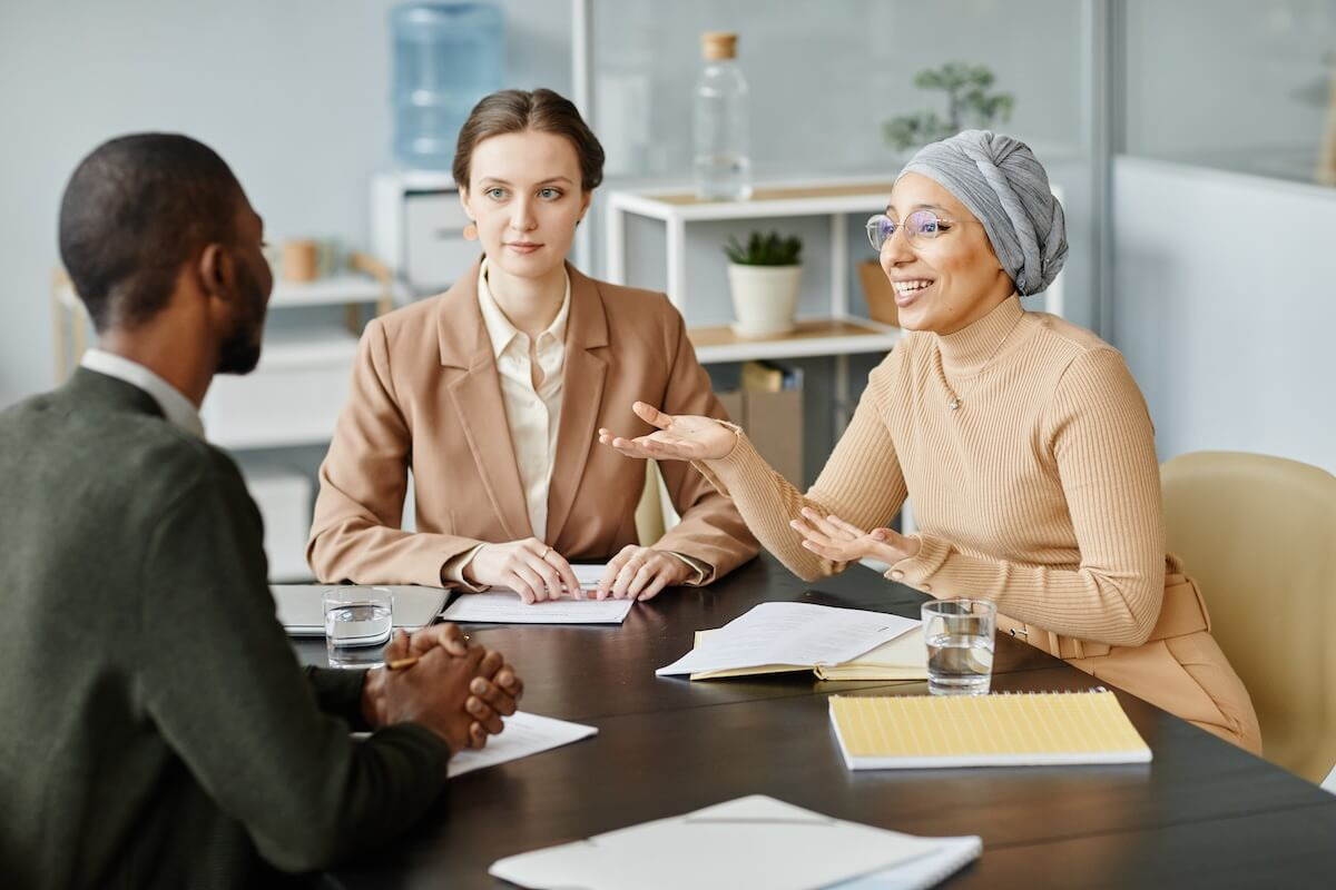 HR compliance cost savings: group of HR staff discussing work matters in their office