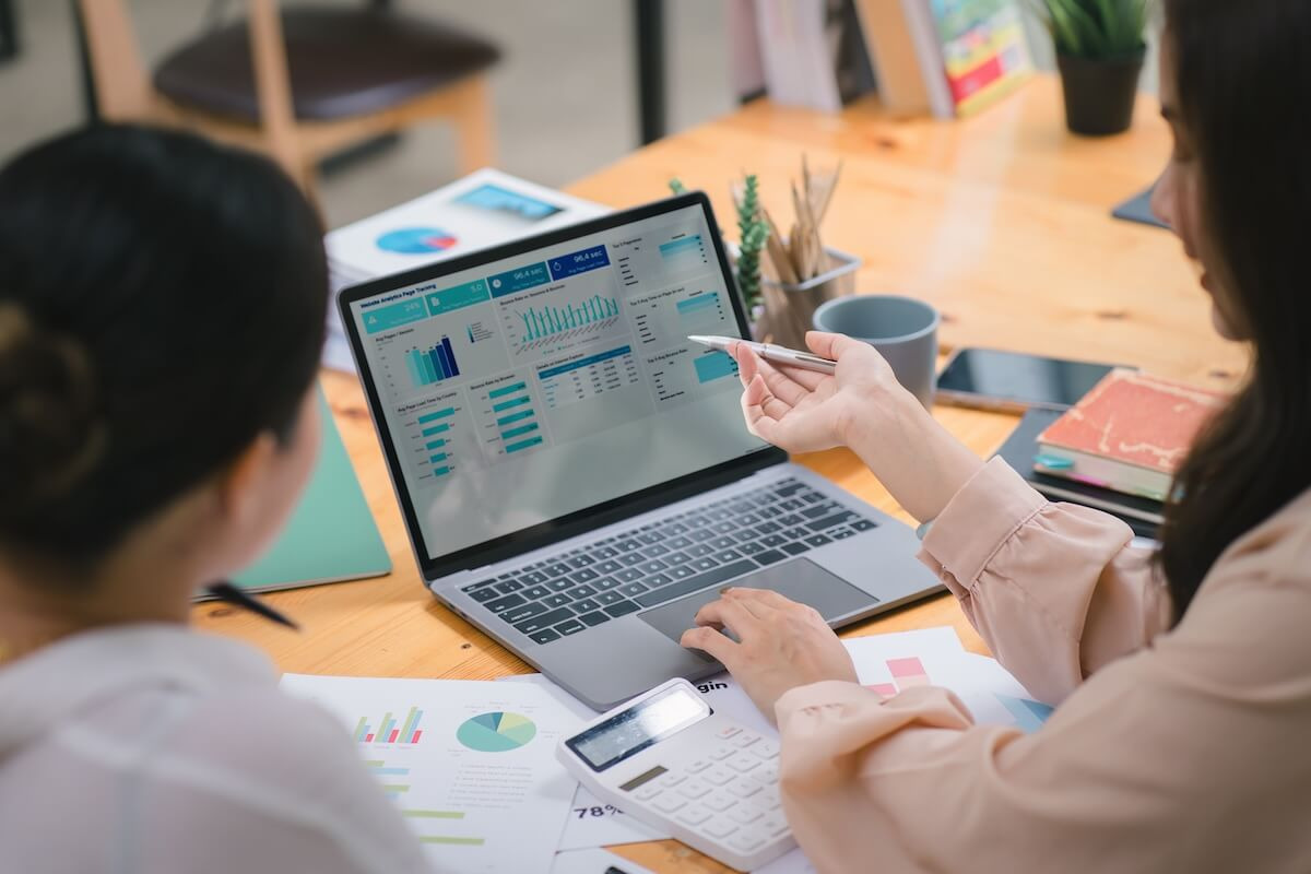 HR employees discussing graphs and data on a laptop