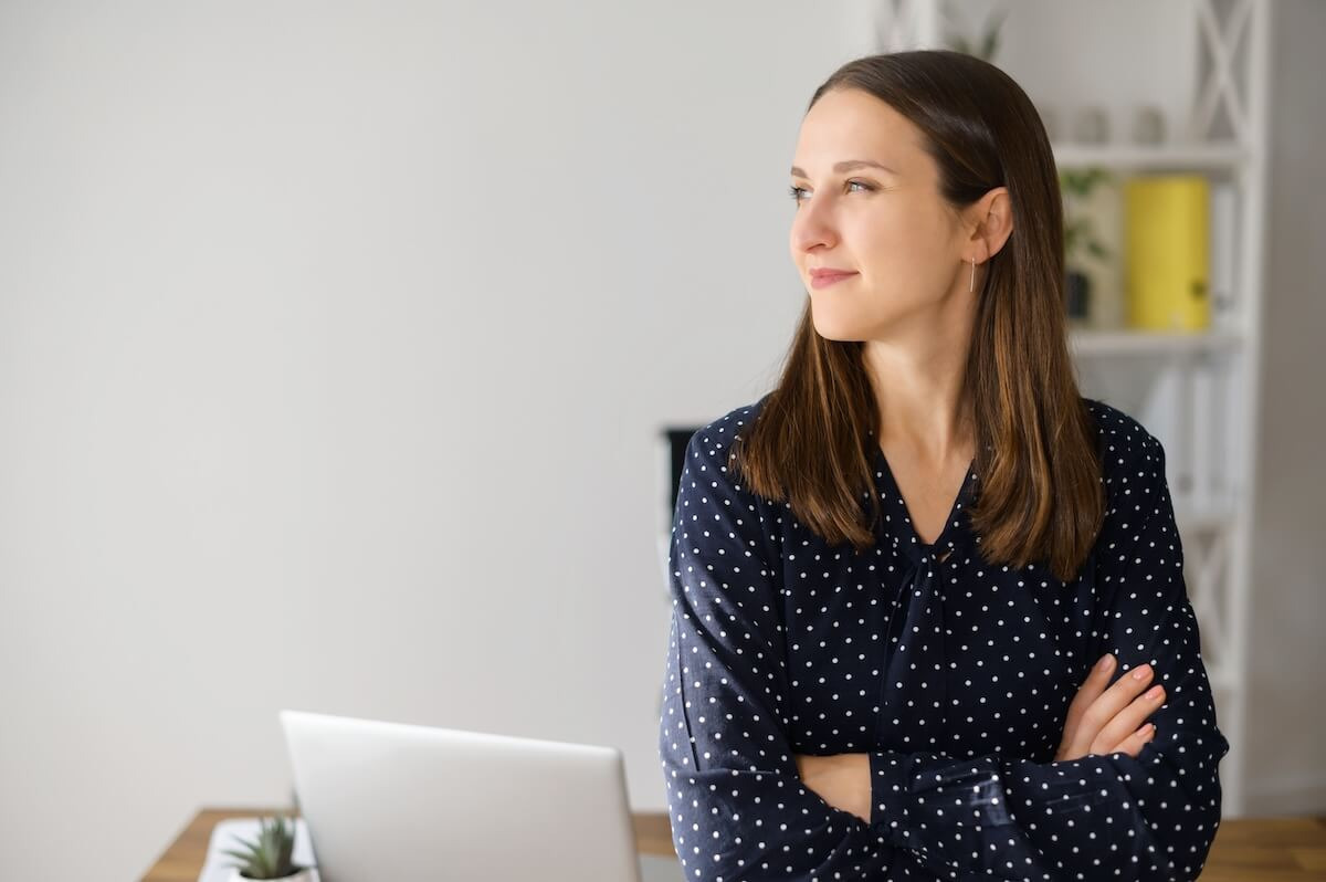 Entrepreneur looking away while standing with her arms crossed