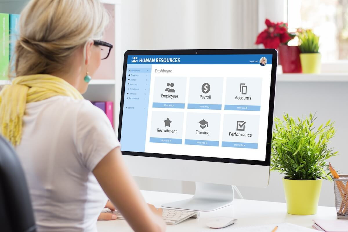 HR manager using her computer, with an HR management dashboard displayed on the monitor