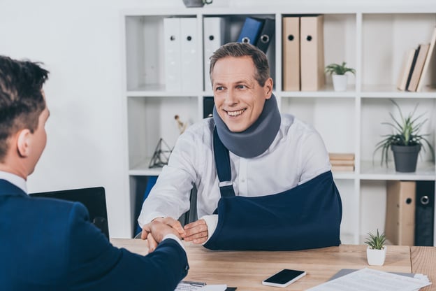 Man wearing a neck brace and an arm sling shaking hands with his manager