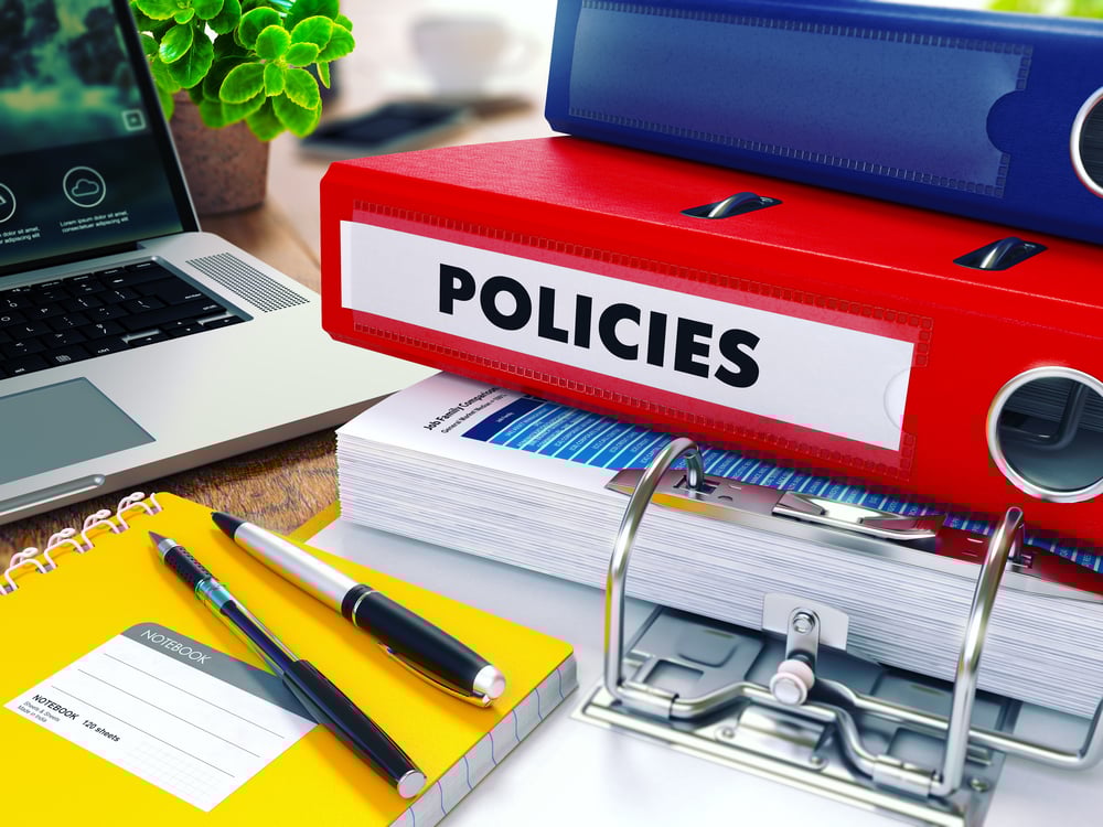 Policies - Red Ring Binder on Office Desktop with Office Supplies and Modern Laptop. Business Concept on Blurred Background. Toned Illustration.