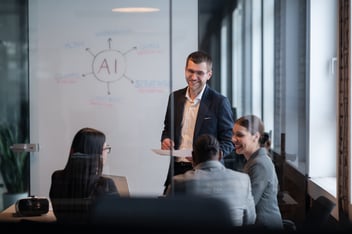 An HR manager and his team meet in a conference room for a fun discussion of why AI helps the workplace.