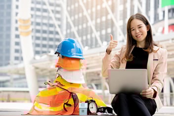 Engineer working on safety concerns while sitting beside a pile of hard hats