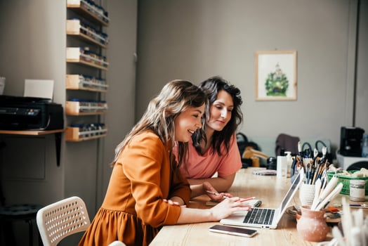 Two women research how leave management software for small business can save them time and money.