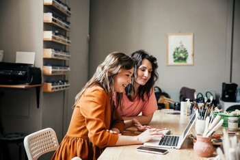 Two women research how leave management software for small business can save them time and money.