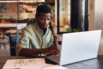 FMLA Florida: man in a wheelchair using a laptop while talking on the phone