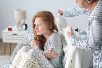 FMLA Michigan: person putting a blanket on a sick woman's back