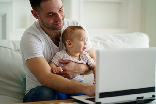 FMLA Maine: father taking care of his baby while using a laptop