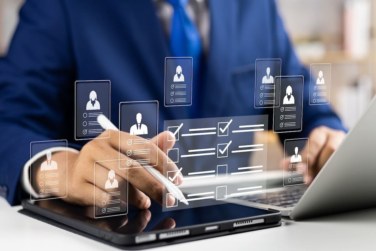 Entrepreneur using a laptop and a tablet with a hologram of user profile icons and a checklist