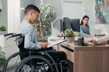 Improving employee leave management: employee in a wheelchair signing a contract