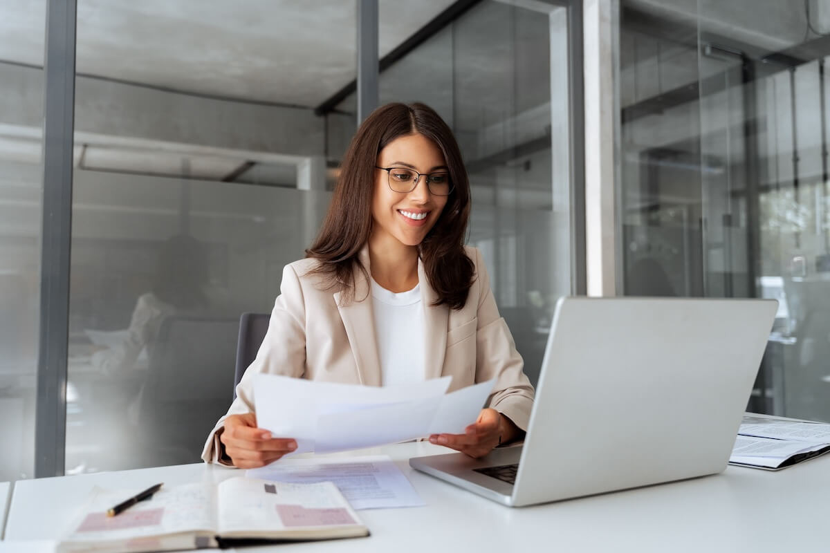 HR technology trends 2026: HR manager looking at a laptop while holding a document