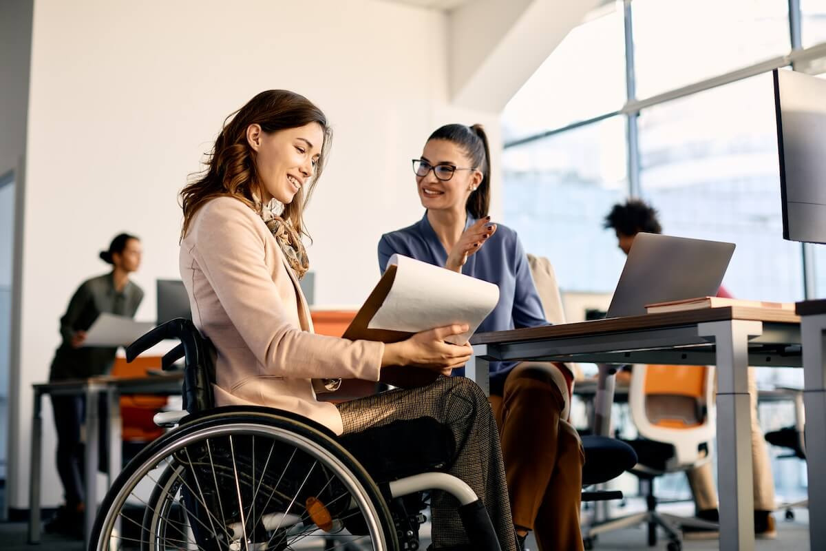 ADA reasonable accommodation checklist: employee in a wheelchair talking to her colleague