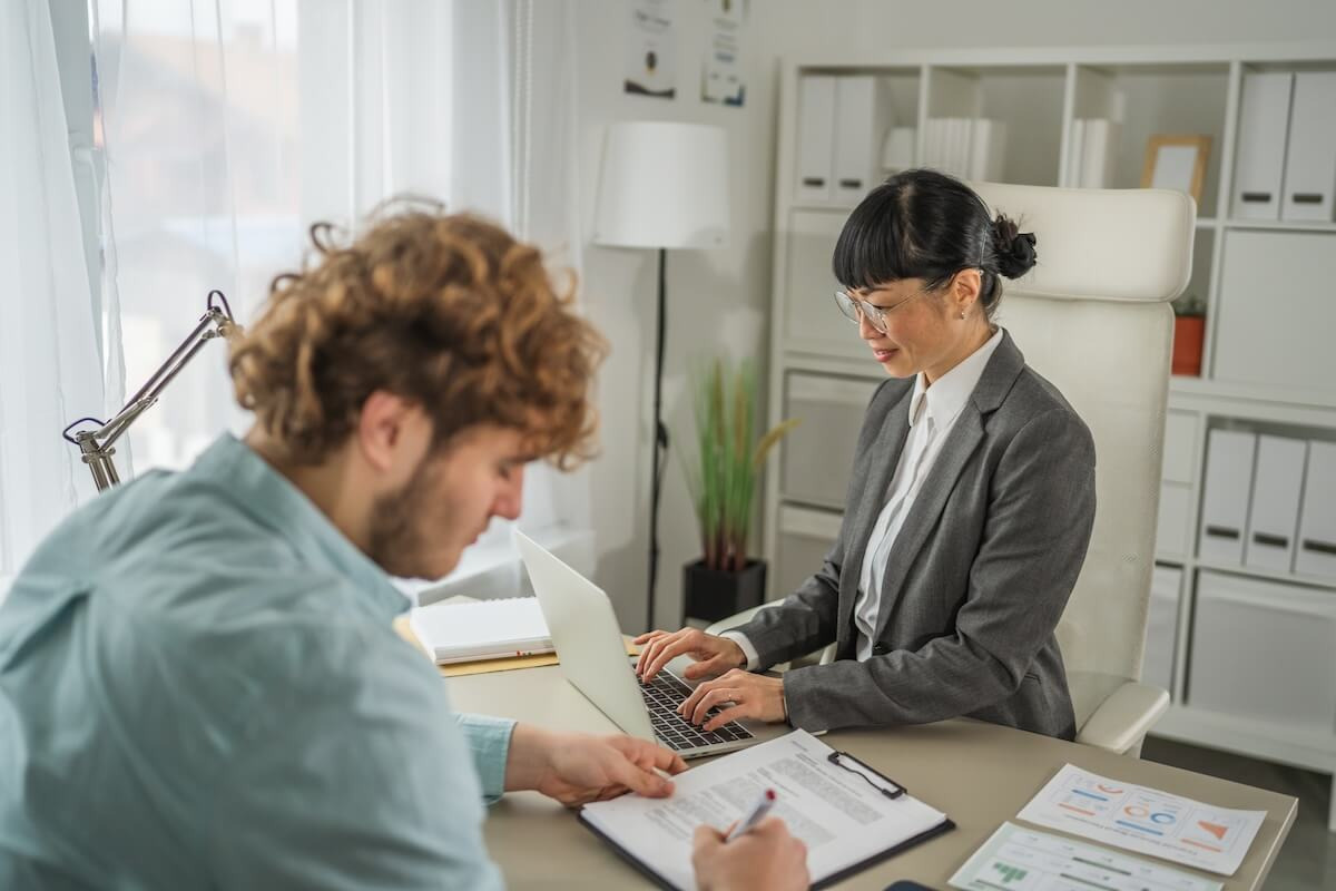 Online leave management system: HR manager using a laptop while an applicant is signing a contract