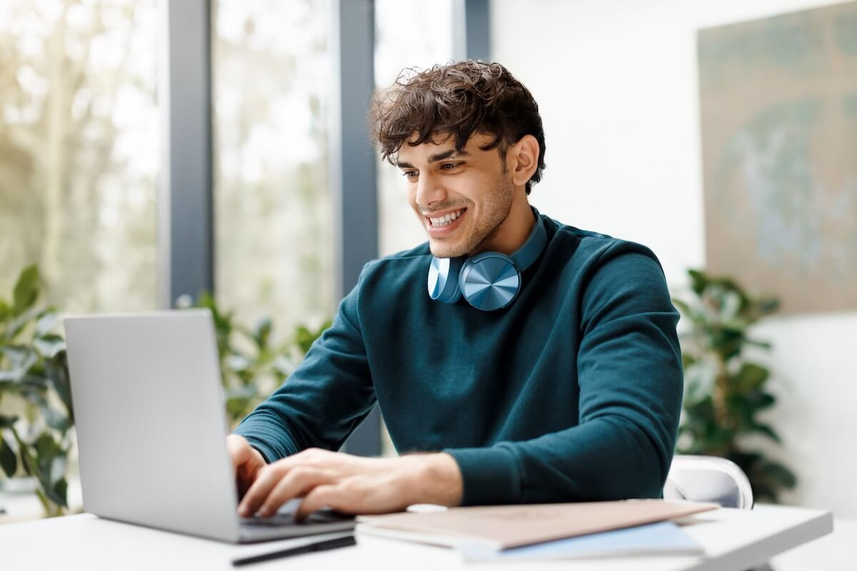 Employee using a laptop with headphones around his neck