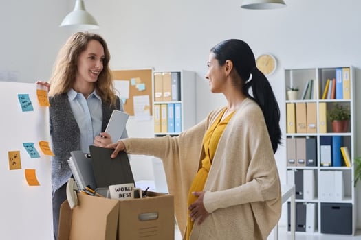 Types of leave of absence: pregnant employee talking to her colleague while packing her stuff