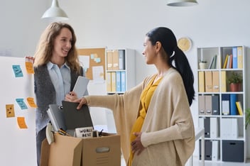 Types of leave of absence: pregnant employee talking to her colleague while packing her stuff