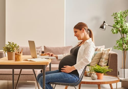 Maine PFML: pregnant woman using her laptop at home