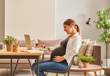 Maine PFML: pregnant woman using her laptop at home