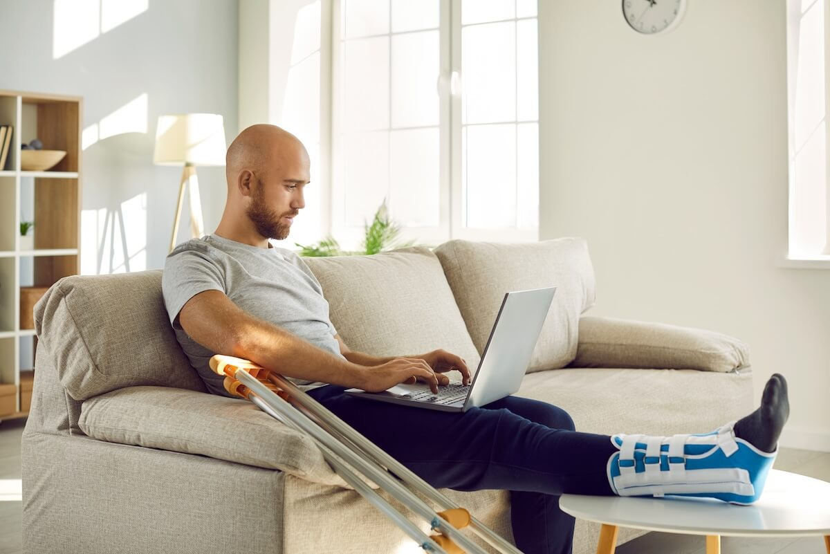 Maine PFML: injured man using his laptop at home