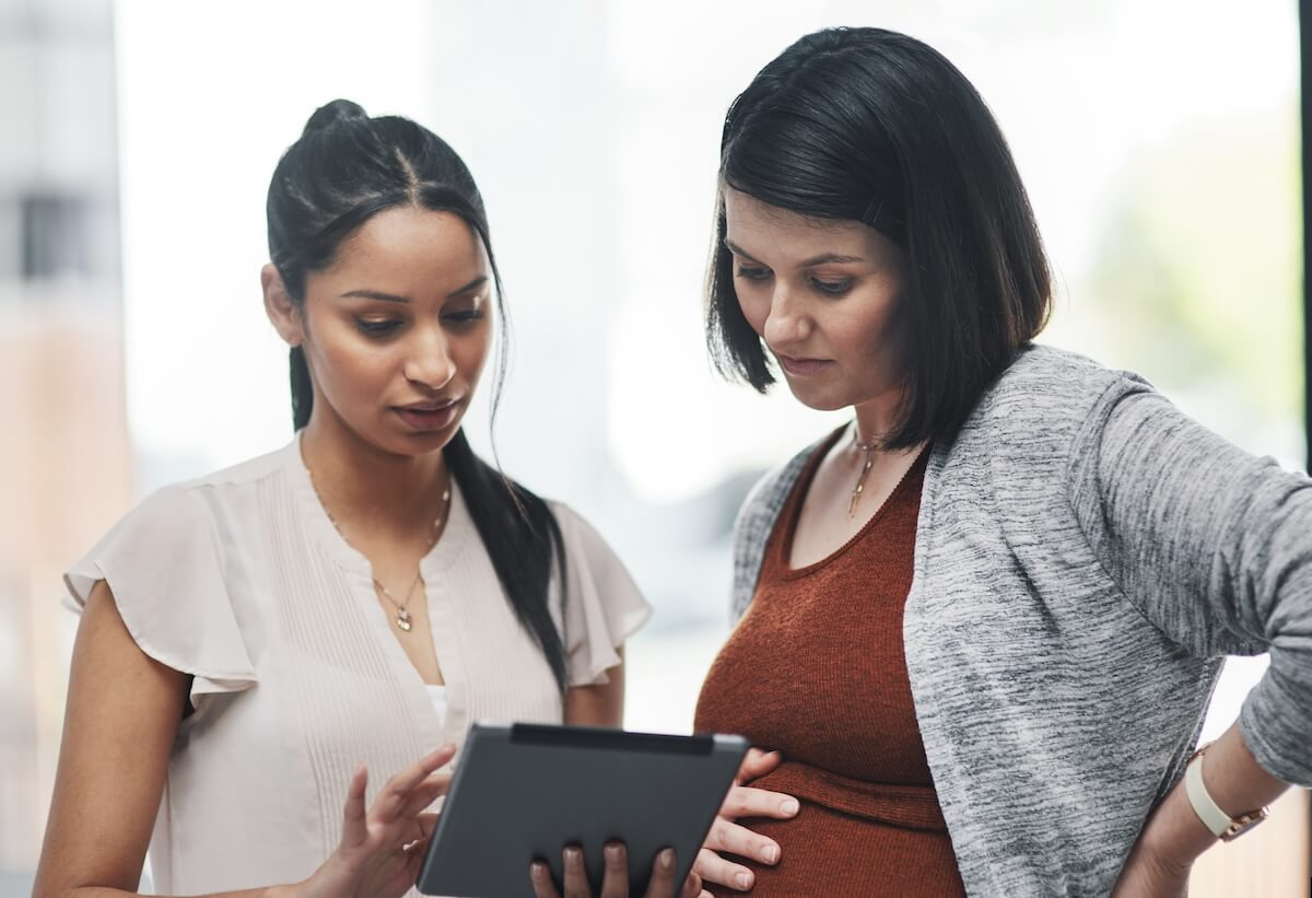 HR leave management system: pregnant entrepreneur and an HR manager looking at a tablet