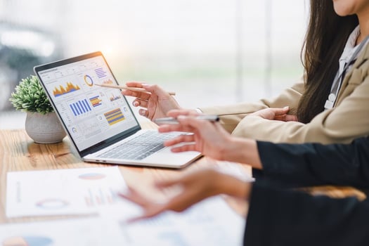 ROI of HR technology: HR employees discussing graphs and data shown on a laptop screen