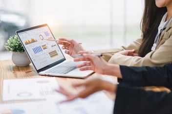 ROI of HR technology: HR employees discussing graphs and data shown on a laptop screen