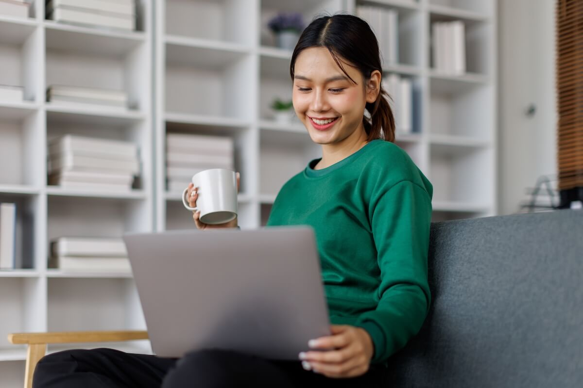 Employee holding a cup of coffee, looking at her laptop