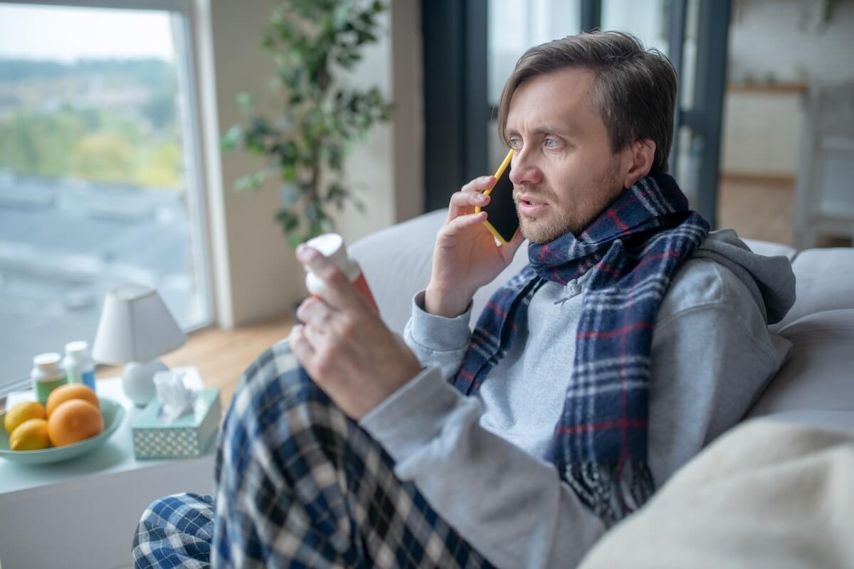 FMLA Washington: man talking on the phone while holding a bottle of medicine