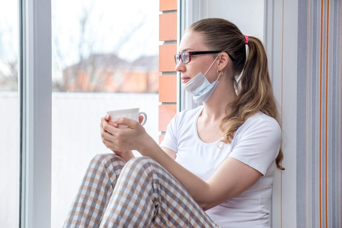Woman wearing a mask while holding a cup of coffee