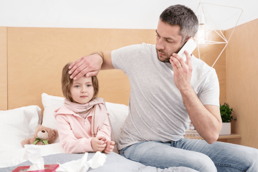 FMLA Washington: father talking on the phone while touching his daughter’s forehead