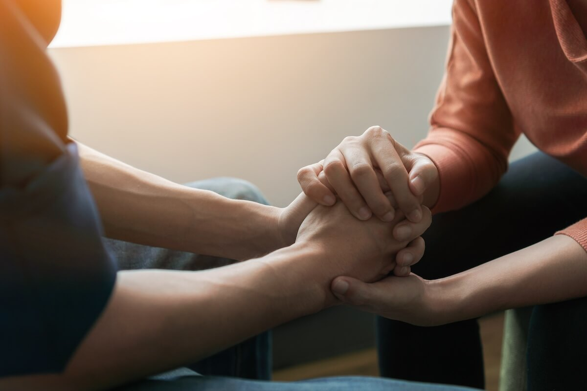 Mental health FMLA: two people holding hands, comforting one another