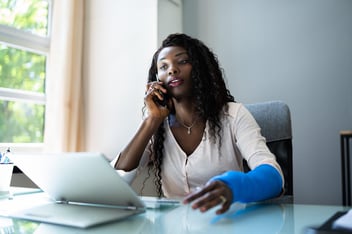 Claim workers compensation: woman with a broken arm talking on the phone